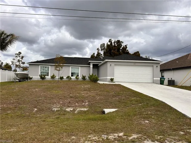 Ranch-style home with a garage, stucco siding, concrete driveway, and a front yard
