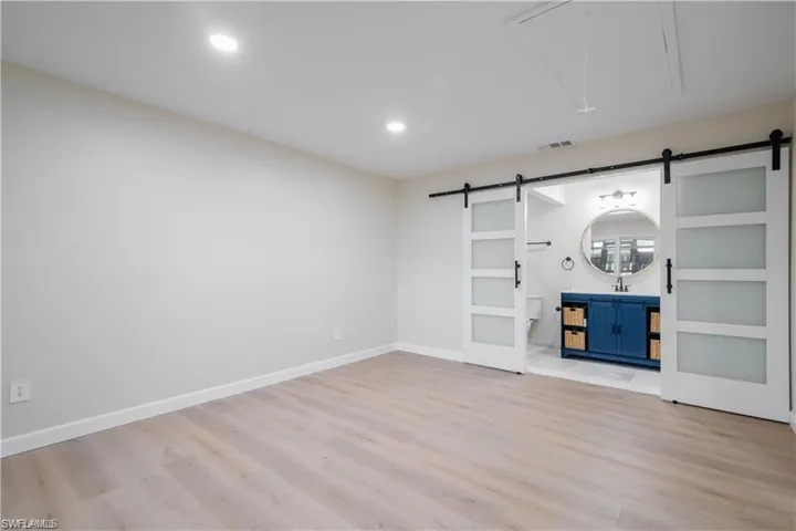 Unfurnished living room with light wood-style floors, attic access, recessed lighting, and a barn door