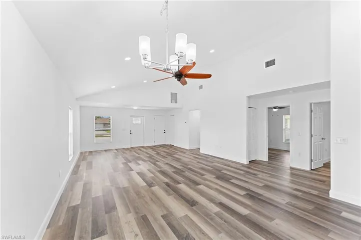Unfurnished living room featuring high vaulted ceiling, light wood-style floors, a chandelier, recessed lighting, and a ceiling fan