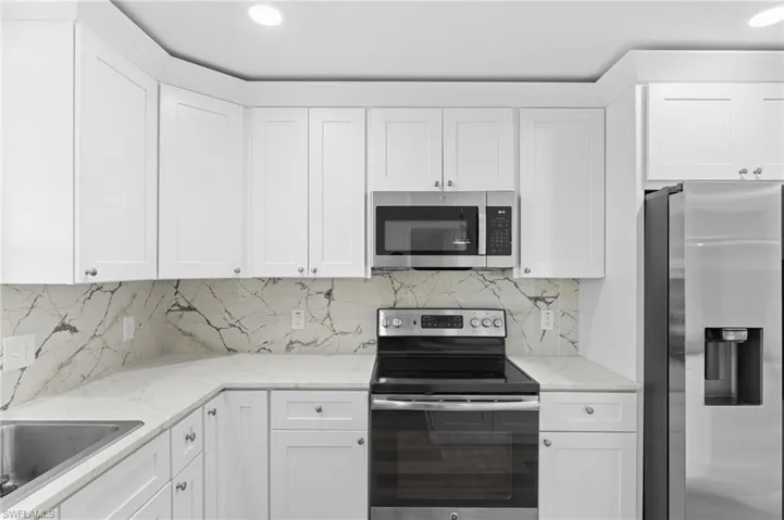 Kitchen featuring appliances with stainless steel finishes, tasteful backsplash, white cabinets, and recessed lighting