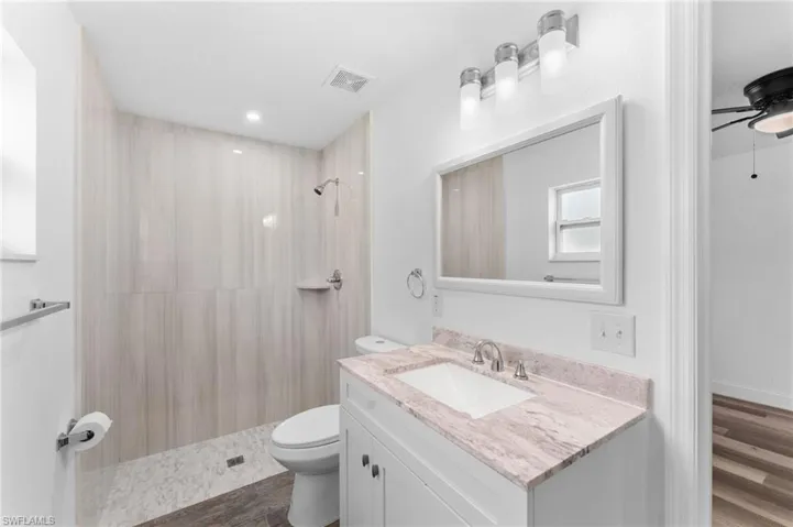 Bathroom featuring a shower stall, a ceiling fan, vanity, dark wood-style flooring, and recessed lighting
