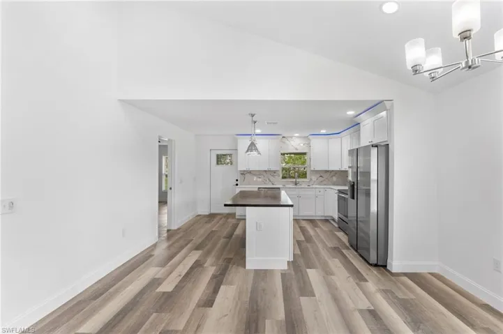 Kitchen with recessed lighting, a kitchen island, decorative light fixtures, lofted ceiling, and white cabinets