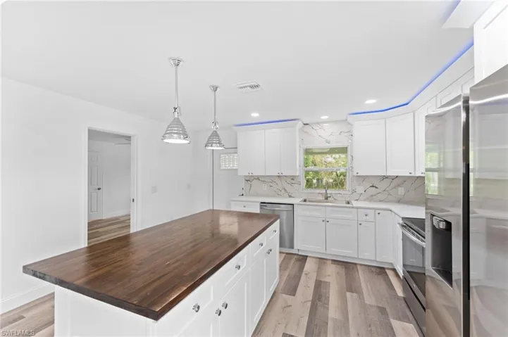 Kitchen featuring wooden counters, light wood-type flooring, pendant lighting, stainless steel appliances, and recessed lighting