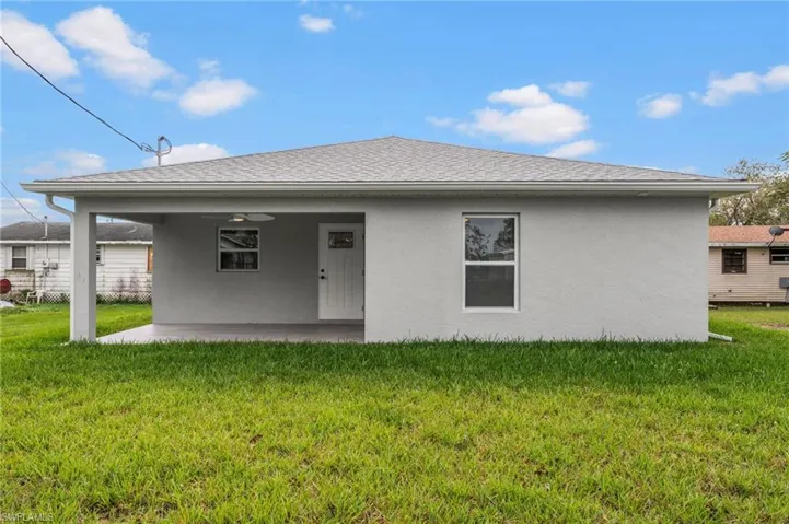 Back of property featuring a patio, a yard, roof with shingles, and stucco siding