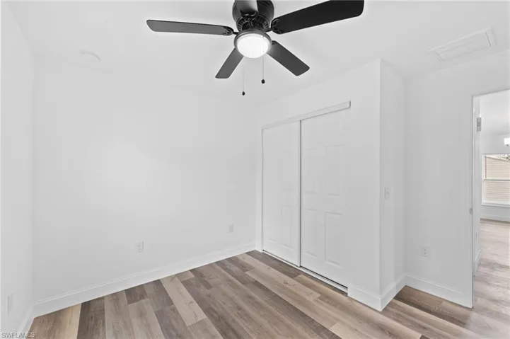 Unfurnished bedroom with light wood-style flooring, a closet, and a ceiling fan