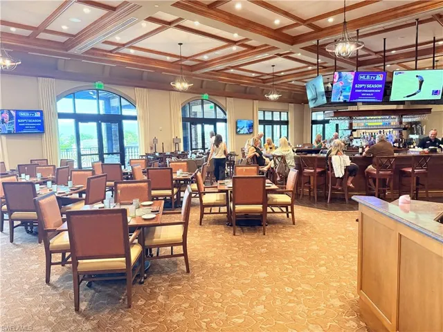 Coffered wood ceiling with recessed lighting, integrated bar area, and arched glass doors