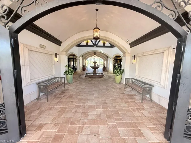 Covered entryway featuring a stone-paved walkway, vaulted barrel ceilings, decorative metalwork, and a central tiered stone fountain