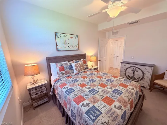 Bedroom featuring carpeted flooring, a ceiling fan with integrated lighting, and a set of double-panel closet doors