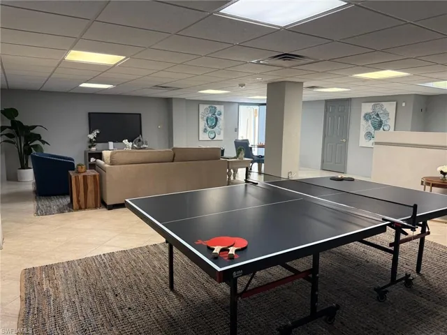PREVIOUSLY STAGED VIEW:Recreation room with a drop ceiling and light tile patterned floors