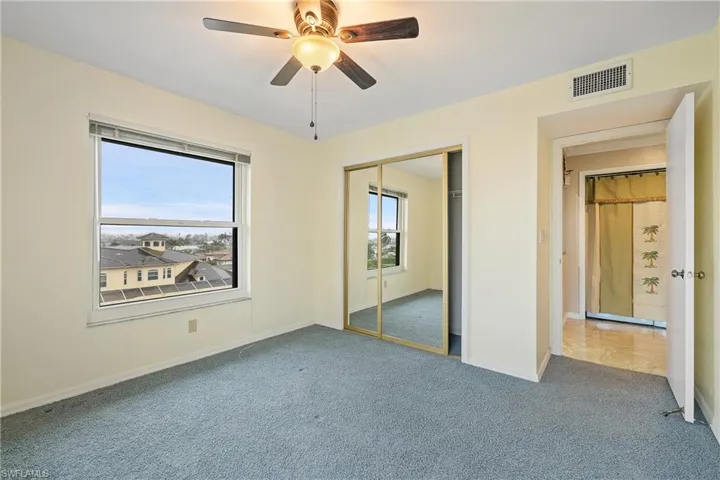 Unfurnished bedroom with multiple windows, carpet, ceiling fan, and a closet