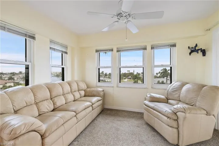 Carpeted living room featuring ceiling fan and plenty of natural light
