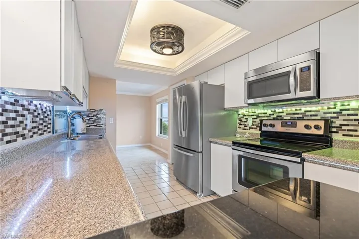 Kitchen with a raised ceiling, white cabinetry, and stainless steel appliances