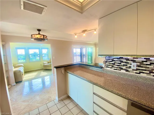 Kitchen featuring  dishwasher, crown molding, track lighting, and tasteful backsplash
