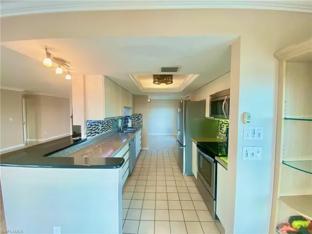 Kitchen featuring stainless steel appliances, kitchen peninsula, sink, a raised ceiling, and white cabinets