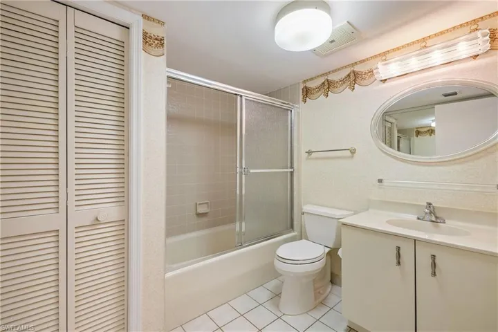 Full bathroom with combined bath / shower with glass door, vanity, toilet, and tile patterned floors