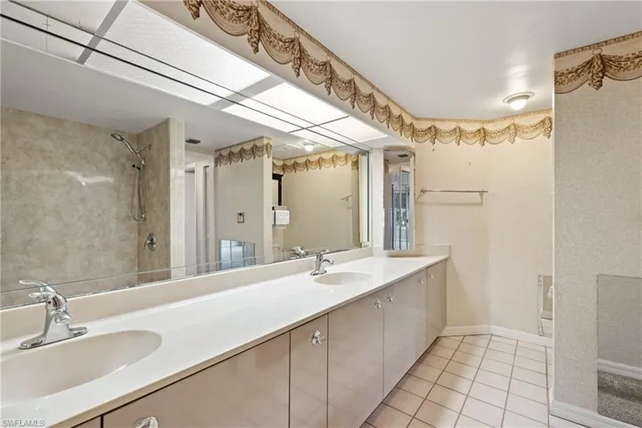 Bathroom featuring a tile shower, tile patterned floors, and vanity