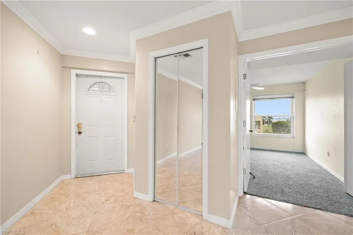 Foyer featuring light colored carpet and crown molding