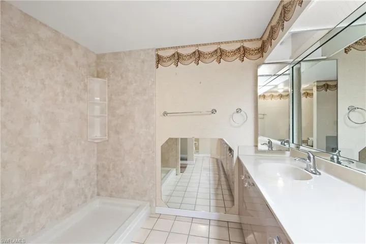 Bathroom with walk in shower, vanity, and tile patterned floors