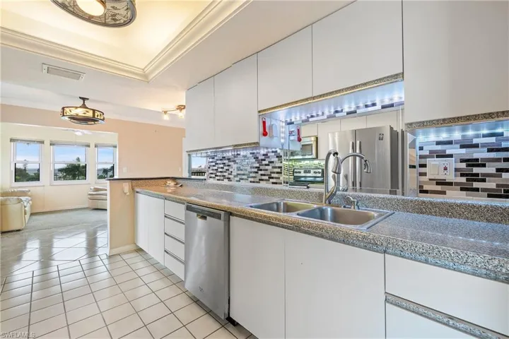Kitchen featuring tasteful backsplash, sink, white cabinetry, stainless steel appliances, and crown molding