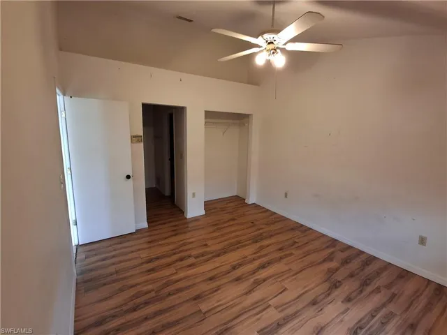 Spacious interior room featuring wood-finish flooring, a ceiling fan with integrated lighting, and an open closet space