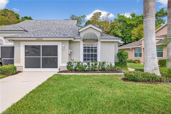 View of front of home with a shingled roof, stucco siding, and a front yard