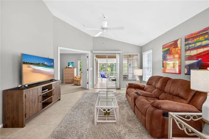Living room featuring lofted ceiling, a ceiling fan, and light tile patterned floors
