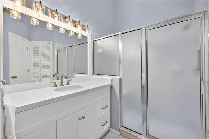 Bathroom with a closet, vanity, and a shower stall
