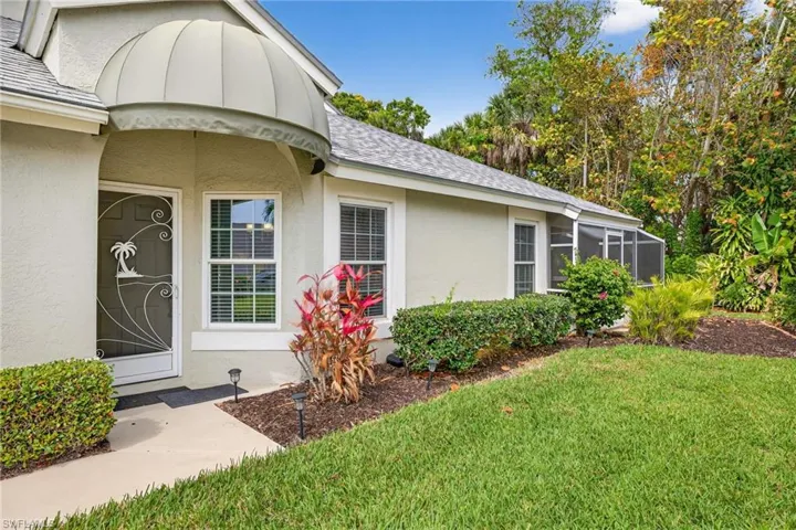 Entrance to property featuring stucco siding, a yard, and a shingled roof