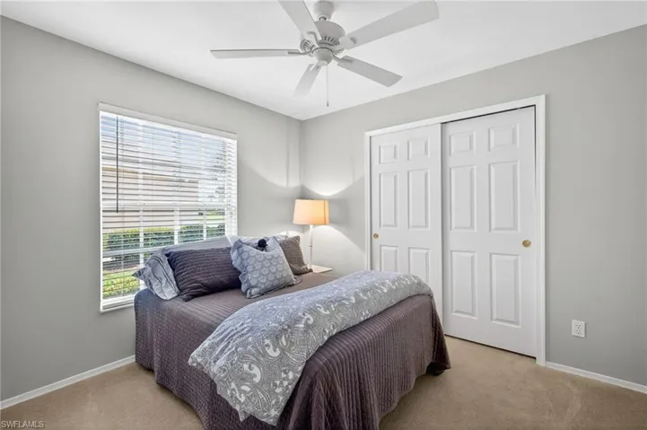 Bedroom with a closet, light colored carpet, and ceiling fan
