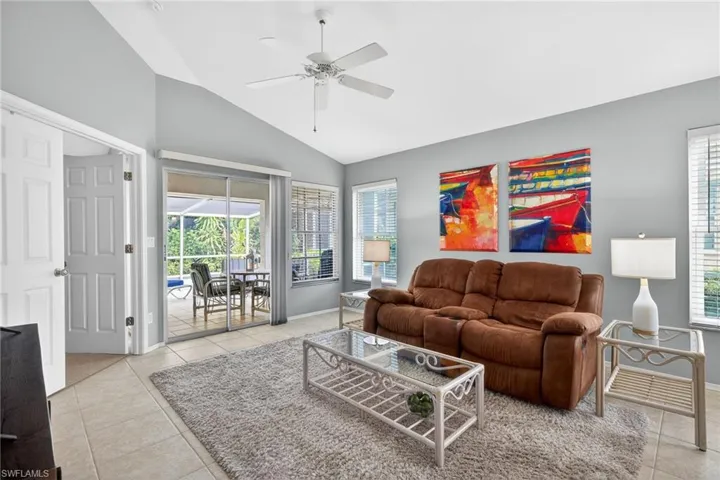 Living area featuring ceiling fan, lofted ceiling, a sunroom, and light tile patterned floors