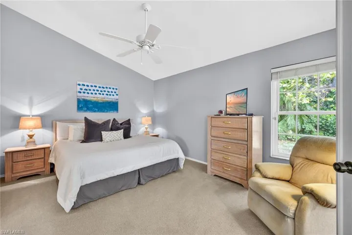 Carpeted bedroom featuring ceiling fan and lofted ceiling