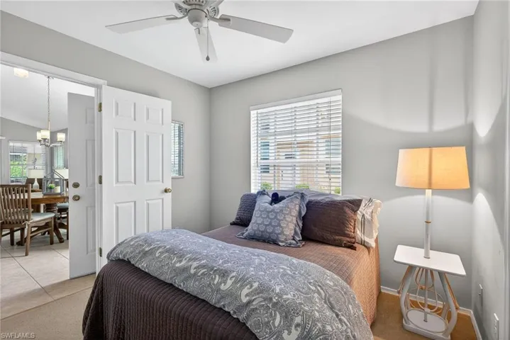 Bedroom featuring multiple windows, light carpet, a ceiling fan, a chandelier, and lofted ceiling