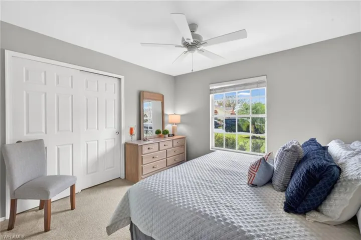 Bedroom with a closet, light colored carpet, and a ceiling fan