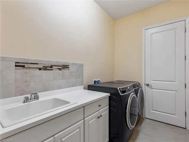 A generous size Laundry Room with a utility sink, storage cabinet, newer washer and dryer, and storage closet which also houses the A/C air handler