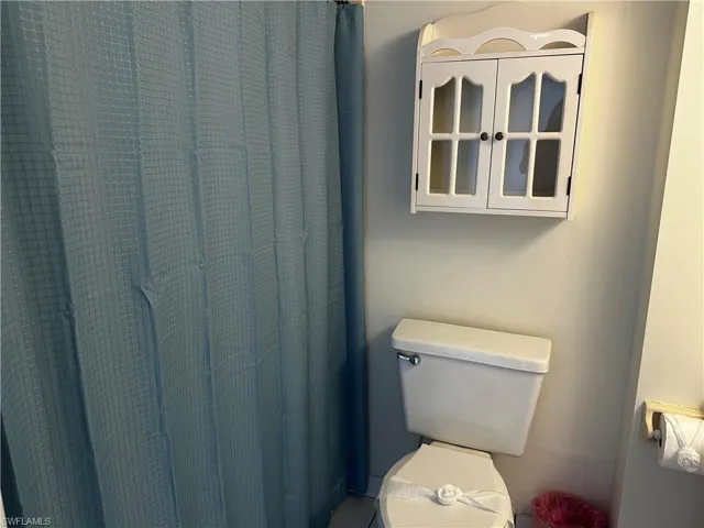 Wall-mounted white cabinet with glass-paneled doors and standard toilet