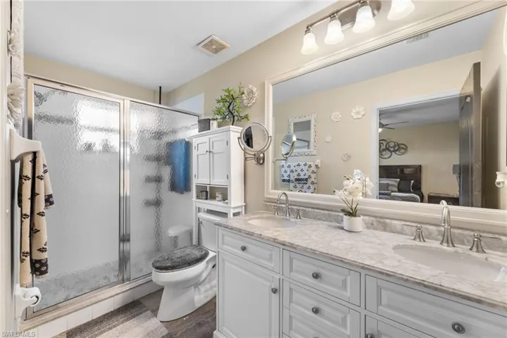 Bathroom with hardwood / wood-style floors, toilet, walk in shower, and vanity
