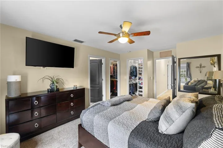 Carpeted bedroom featuring ceiling fan, a closet, and a walk in closet