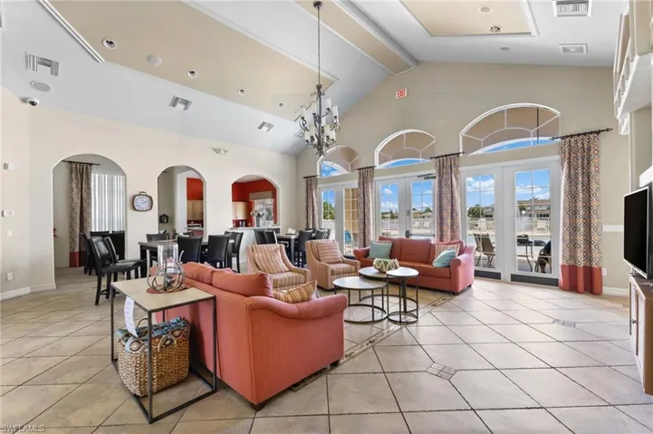 Tiled living room with an inviting chandelier, a towering ceiling, and french doors