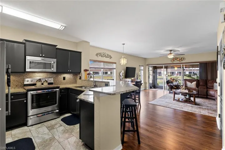 Kitchen featuring appliances with stainless steel finishes, decorative light fixtures, sink, kitchen peninsula, and a breakfast bar