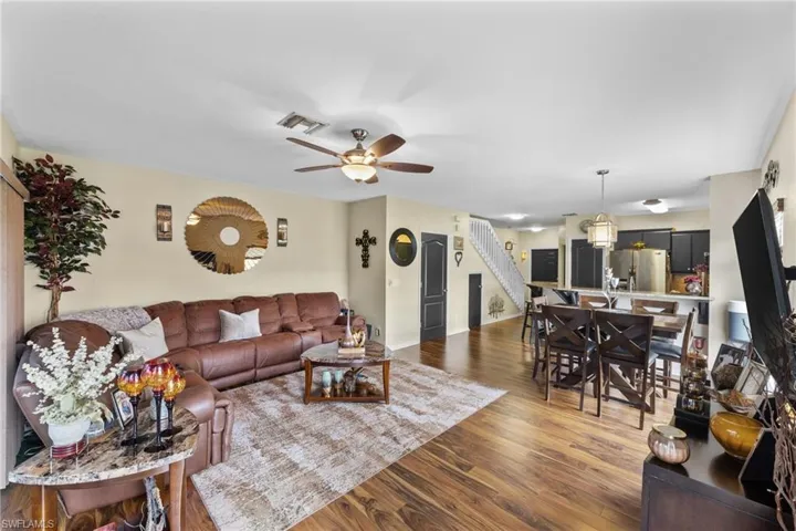 Living room featuring ceiling fan and dark wood-type flooring