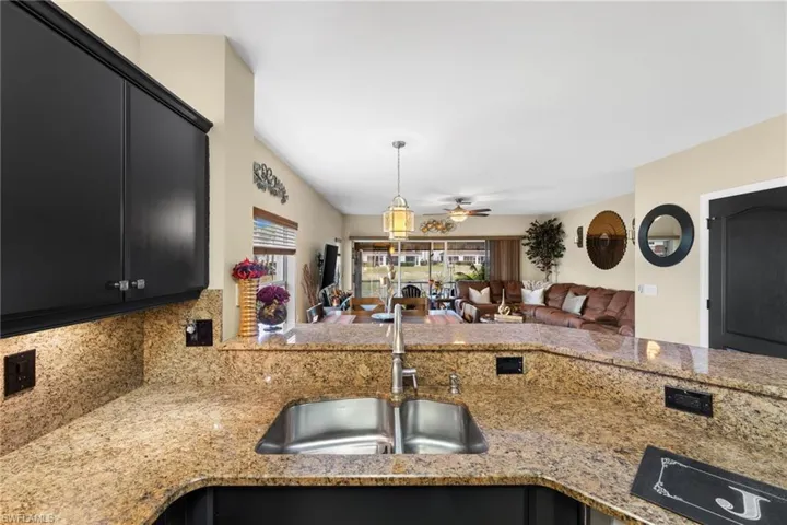 Kitchen featuring kitchen peninsula, pendant lighting, ceiling fan, sink, and light stone counters
