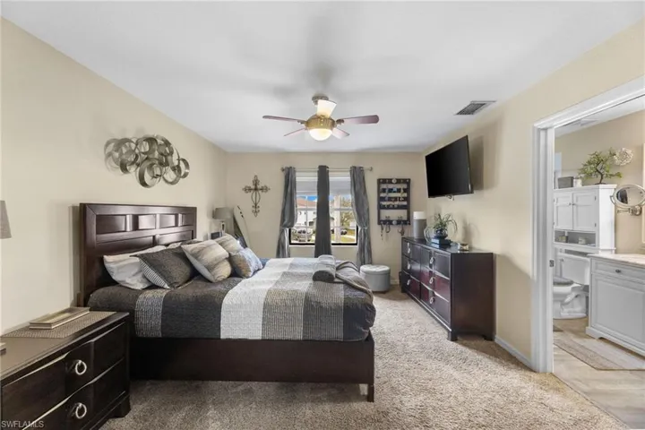 Carpeted bedroom with ceiling fan and connected bathroom
