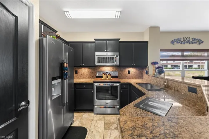 Kitchen with sink, backsplash, stone counters, and stainless steel appliances
