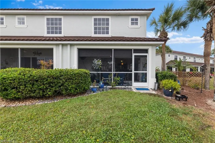 Rear view of house featuring a sunroom and a lawn