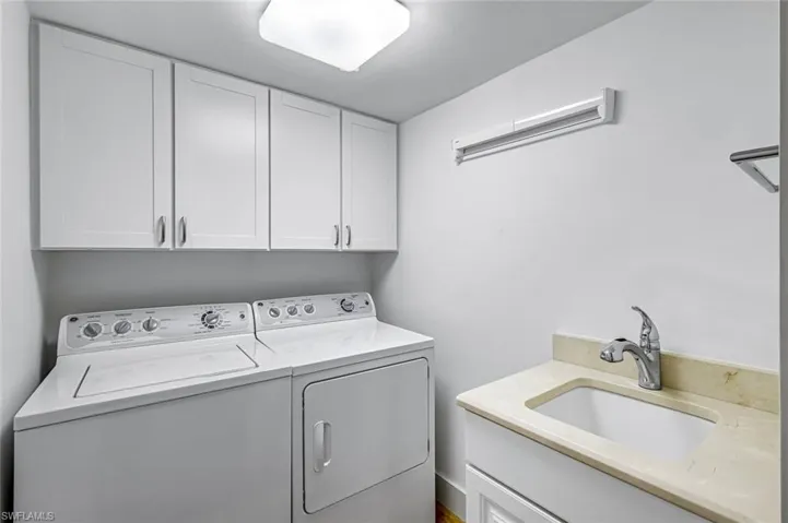 Laundry room featuring cabinet space, full size washer and dryer and independent sink