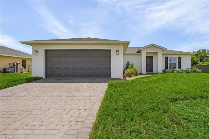 Ranch-style house featuring a garage, central air condition unit, and a front yard