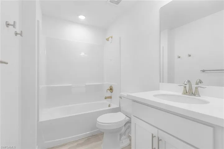 Full bathroom featuring hardwood / wood-style flooring, toilet, shower / tub combination, and vanity
