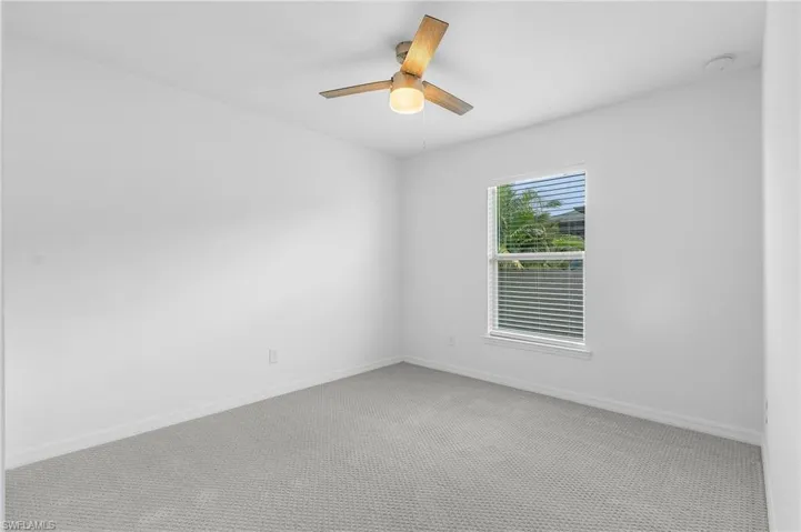 Carpeted spare room featuring ceiling fan