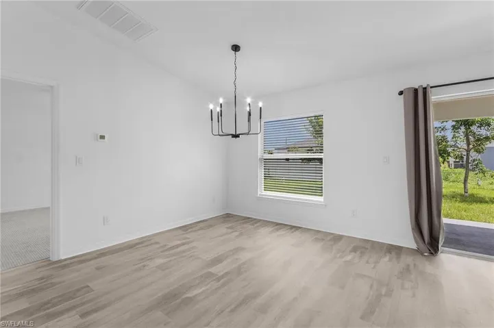 Spare room featuring a notable chandelier and light wood-type flooring