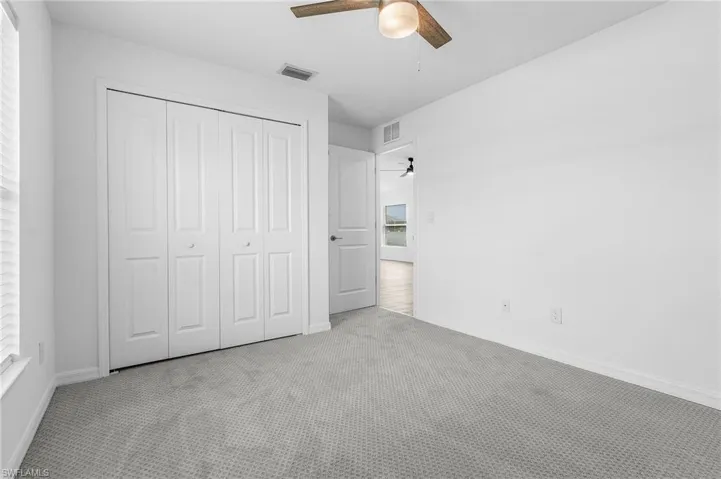 Unfurnished bedroom featuring carpet floors, ceiling fan, and a closet